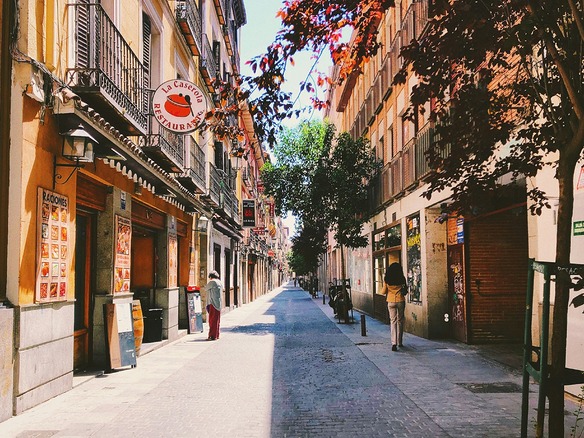 Calle peatonal de un barrio del centro de Madrid con edificios clásicos, balcones y vecinos paseando