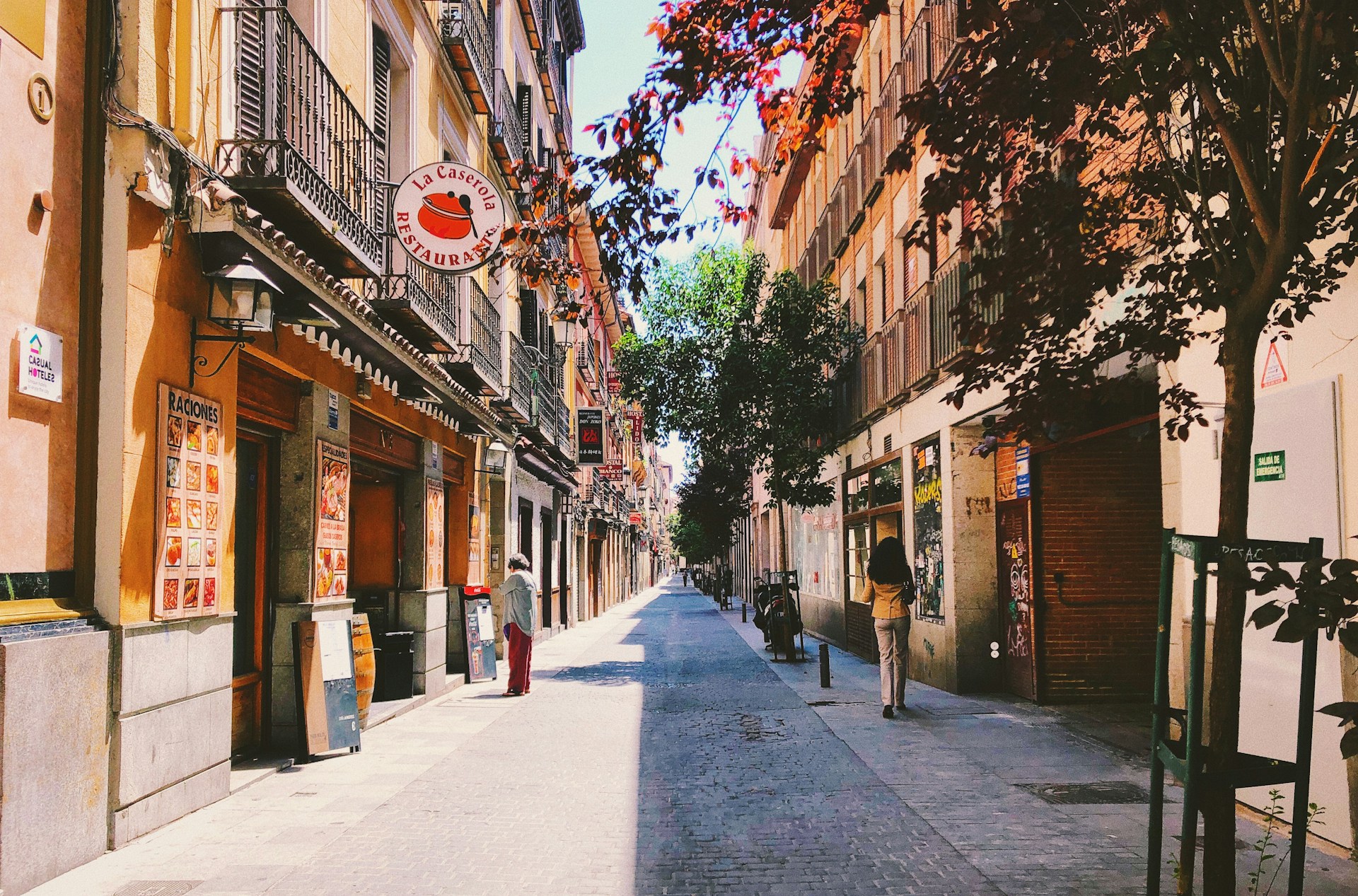 Calle peatonal de un barrio del centro de Madrid con edificios clásicos, balcones y vecinos paseando