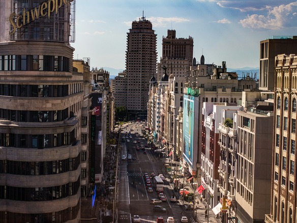 Vista elevada de la Gran Vía de Madrid a media tarde, con tráfico, aceras concurridas y fachadas históricas bajo el sol