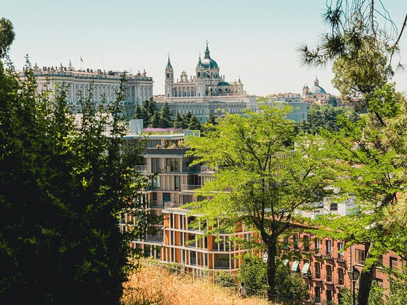 Vista de Madrid con el Palacio Real y la catedral de la Almudena al fondo, arboledas verdes y bloques de viviendas con terrazas